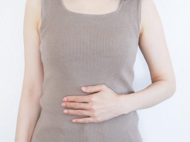 腹部を押さえる女性