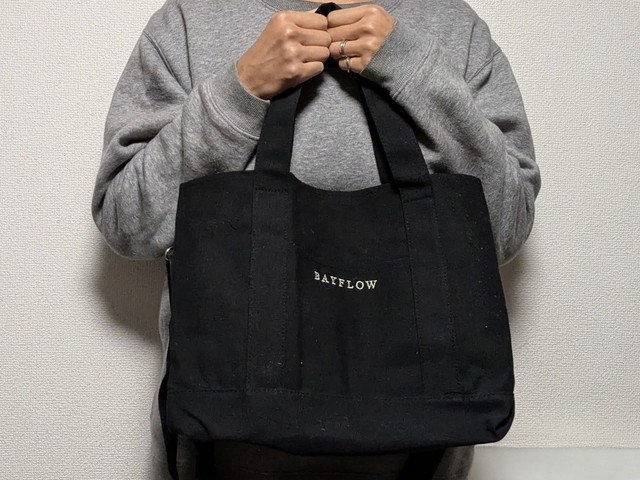 BAYFLOWの黒トートを手持ちしている正面カット。マチがしっかりありスクエア気味のフォルム