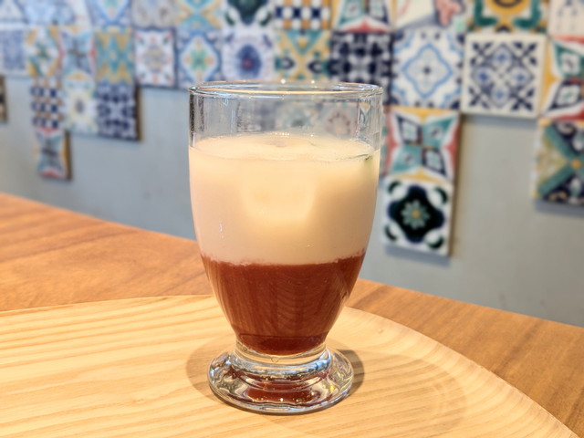 グラス底に赤いいちごソース、上にアーモンドミルクが重なった鮮やかな二層のドリンク