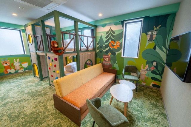 Play!! RESI STAYの森テーマ客室。緑の壁にボルダリング付きロフトベッドがある子ども部屋