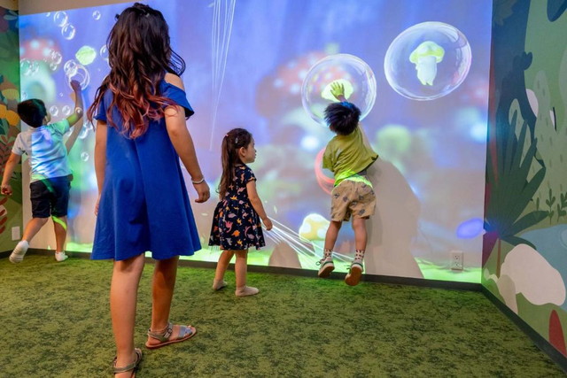 Play!! RESI STAYのプロジェクションゲームコーナー。子どもたちが壁いっぱいのプロジェクション映像で遊んでいる