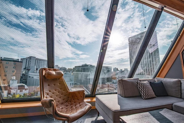 浅草九倶楽部ホテルのスタイリッシュな客室。斜め大窓から都市の景色が一望できるラウンジスペース