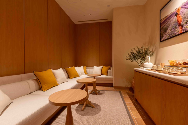 SPA L'OCCITANE EN PROVENCEのリラクゼーションルーム。イエローのクッションが並ぶソファとハーブティーコーナー