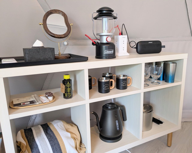 ドームテント内の設備棚。コールマンのランタン、ケトル、マグカップ、Bluetoothスピーカーなどが揃う