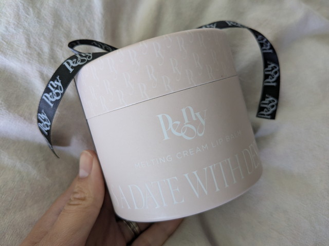 Peony Special Bookのメルティングクリームリップバームの丸い外箱を手に持ったようす