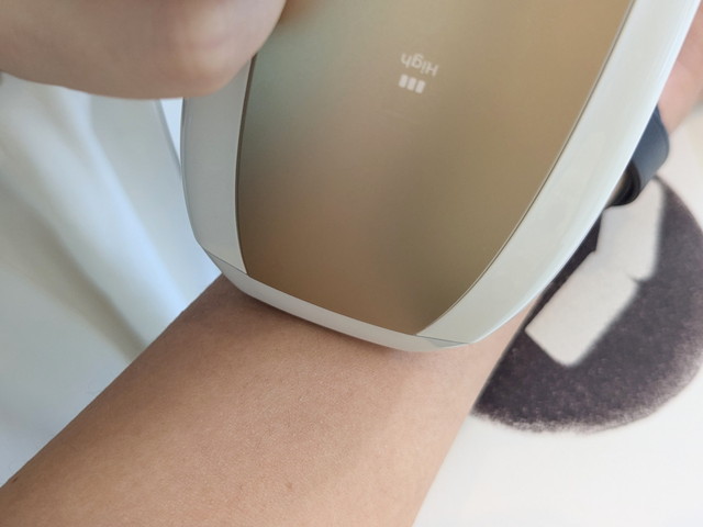 Ulike IPL光美容器のシャンパンゴールドモデルを腕に当てて照射している様子