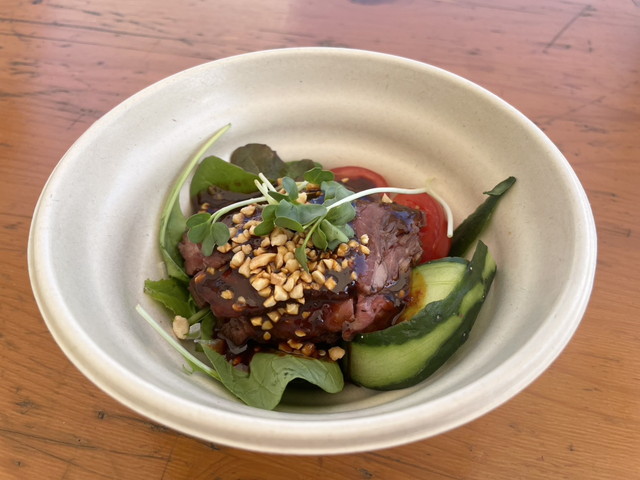 赤坂四川飯店の口水牛肉（よだれ牛）。白い器にルッコラやトマト、きゅうりと共に牛肉が盛られ、砕いたナッツと濃厚なタレがかかっている