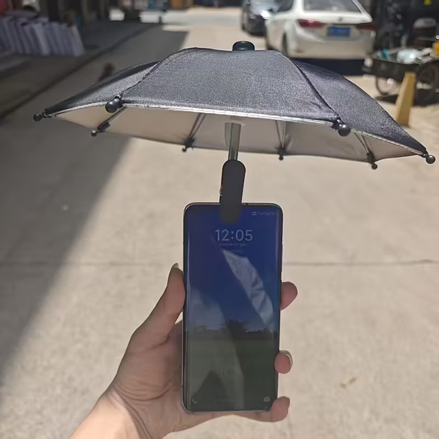 ミニサイズのサンシェードパラソルをスマホにクリップで取り付けて屋外で手に持っている様子