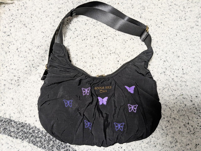 ANNA SUI mini 2wayクロワッサンバッグ正面。ブラックのクシュ素材に蝶の刺繍と立体パーツが散りばめられている