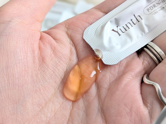 Yunth生PDRN-α美容液のテクスチャーを手のひらに出したアップ。琥珀色のとろみのある美容液が確認できる