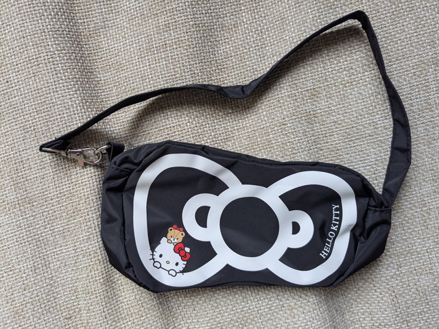 ハローキティリボン型ミニBAGの正面アップ。黒地に白のリボンとキティちゃんのイラストが描かれている