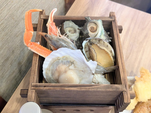 木箱に入ったカニ脚やホタテ、あわび、サザエなどの浜蒸し食材