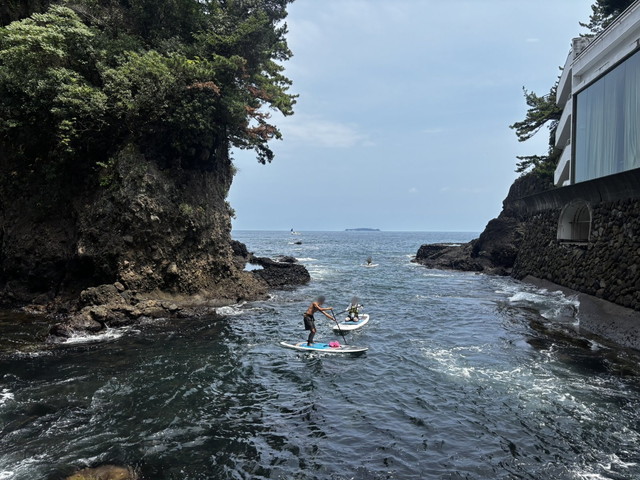 海でSUPを楽しむ人たちとホテルの外観