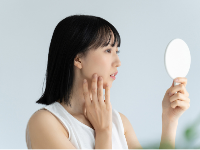 鏡で肌をチェックする日本人女性