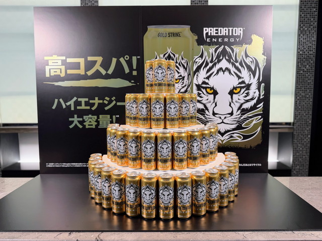 「高コスパ！ハイエナジー！大容量！」のパネル前にタワー状に積まれたゴールドの『プレデターエナジー』缶