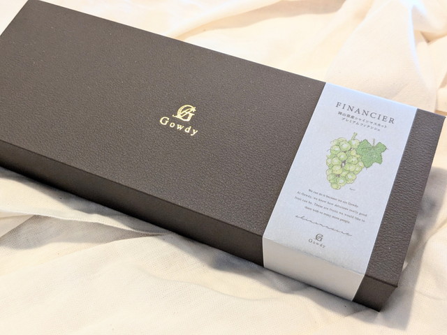 ガウディのロゴが入った「岡山県産シャインマスカット プレミアムフィナンシェ」の化粧箱
