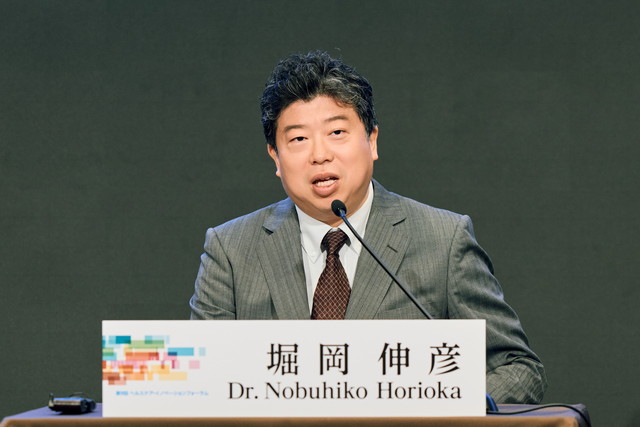 登壇して話す厚生労働省の堀岡伸彦健康課長